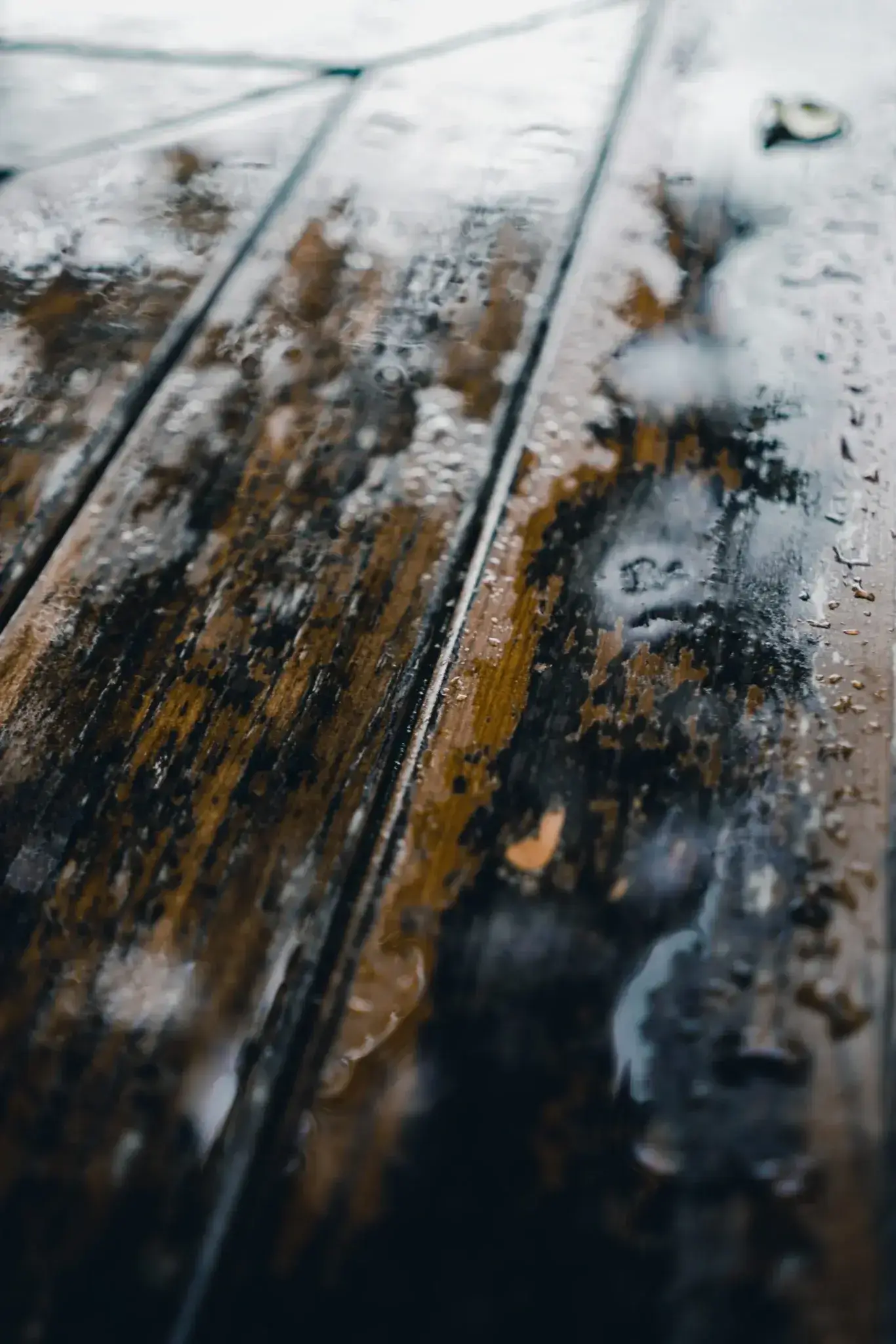 A close up of the wood surface with water droplets on it.