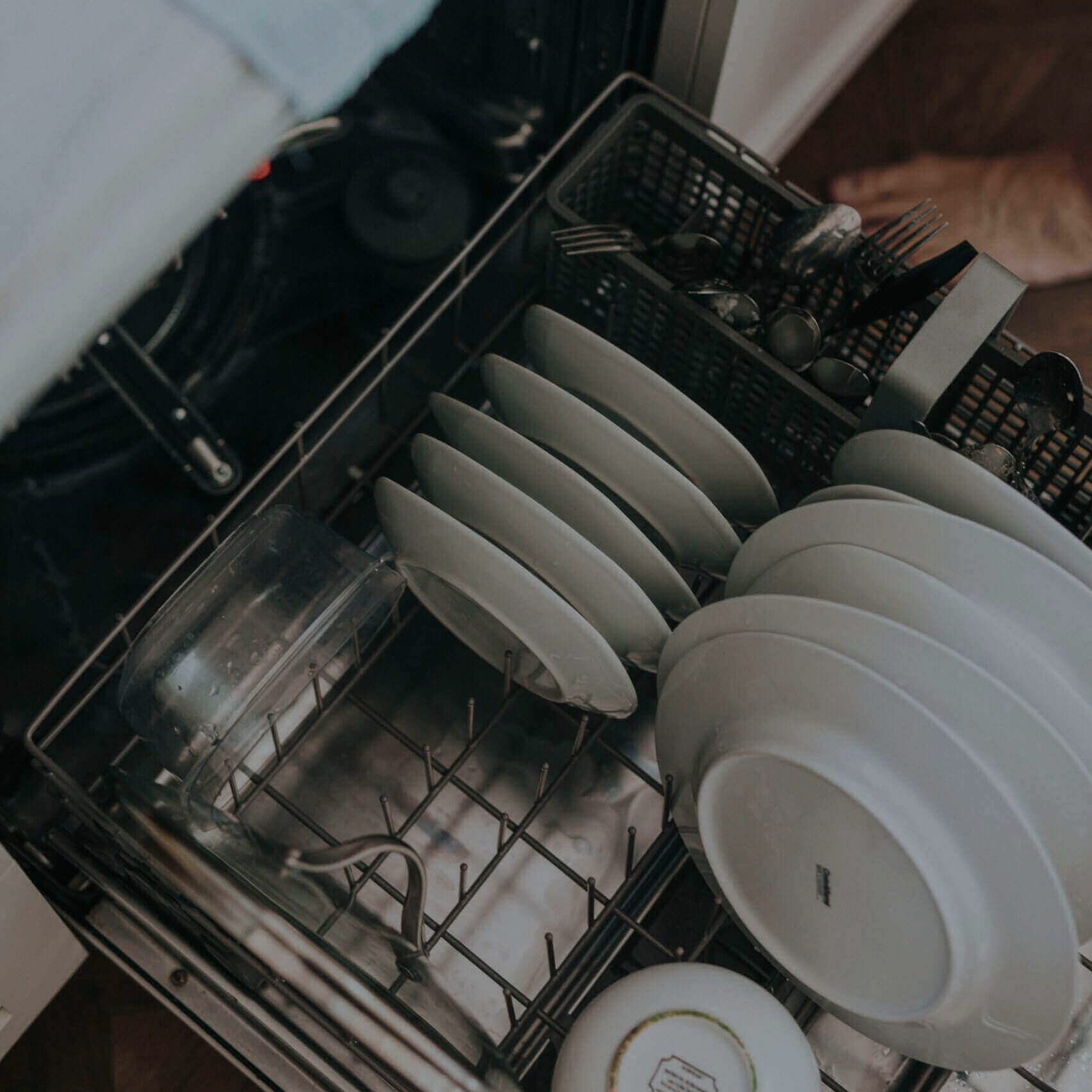 Open dishwasher loaded with plates and utensils