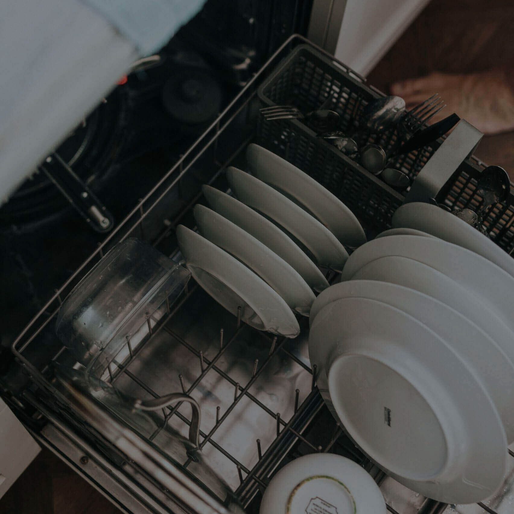 Open dishwasher loaded with plates and utensils