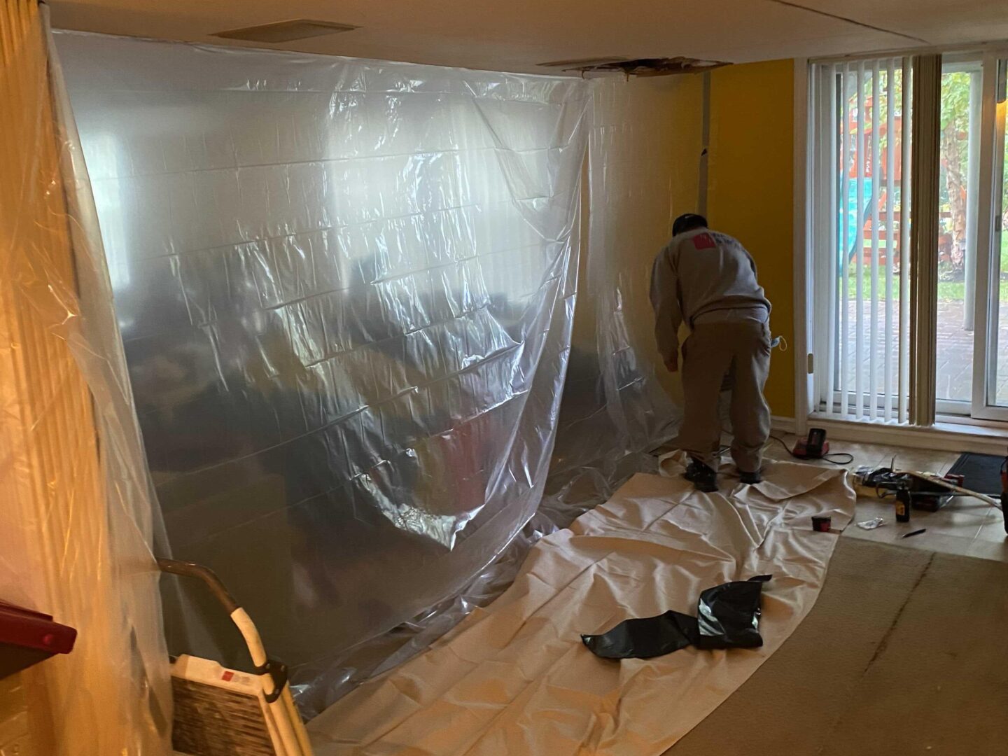 A man in a room covered with plastic sheeting.