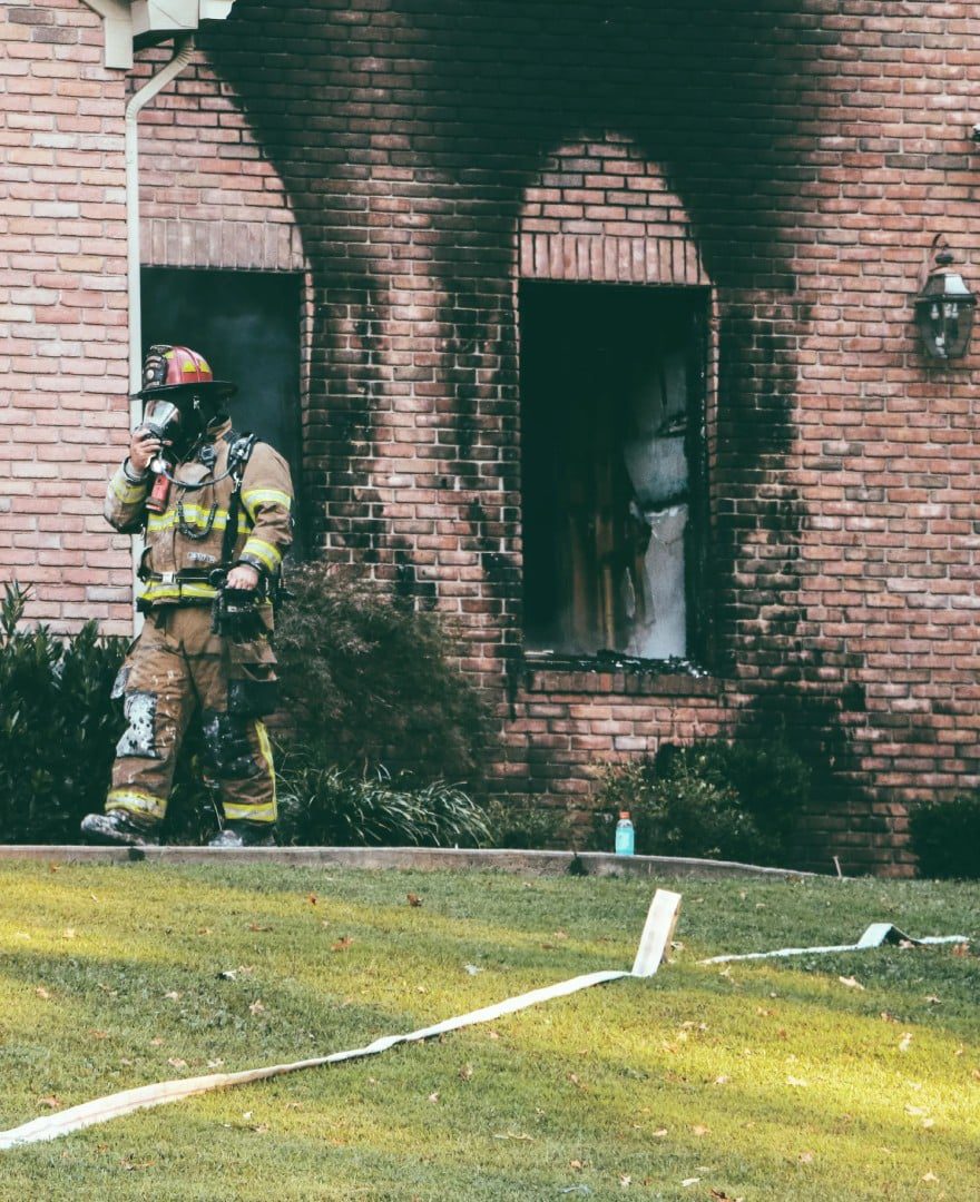 A fireman is standing outside of the house